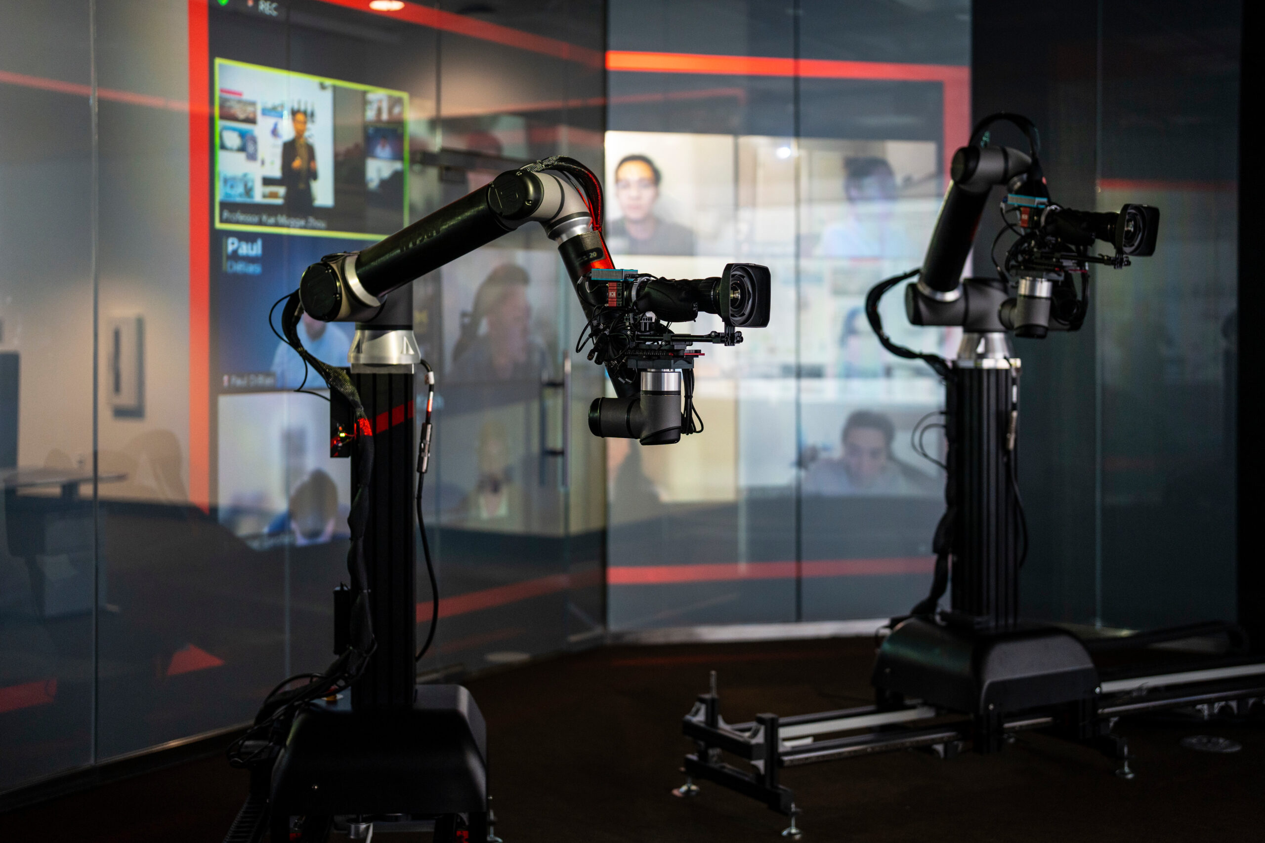 The dynamic cameras in a dark digital learning studio. There is a reflection that shows a Zoom room. 