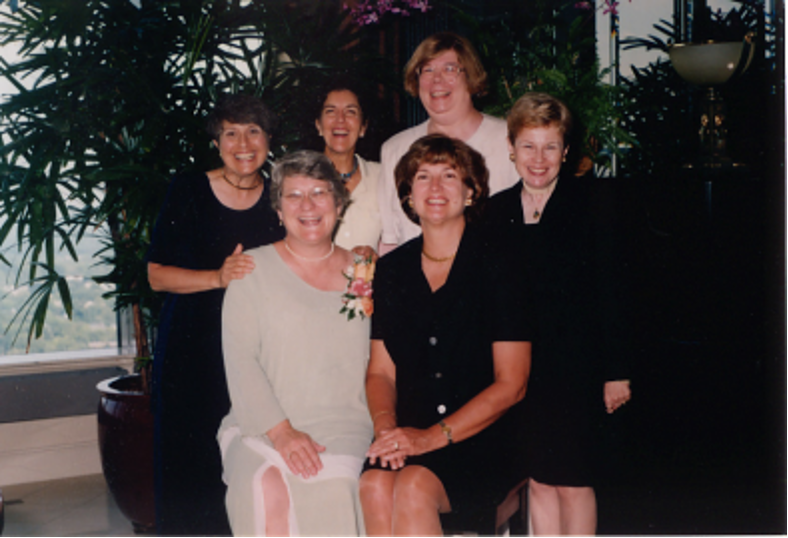 "The Roomies" in dress clothes pose together in an indoor setting. 