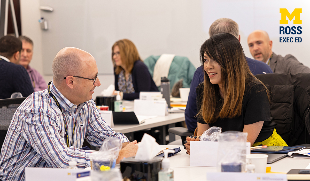 Two people conversing at a table as part of the Michigan Ross Executive Education program.