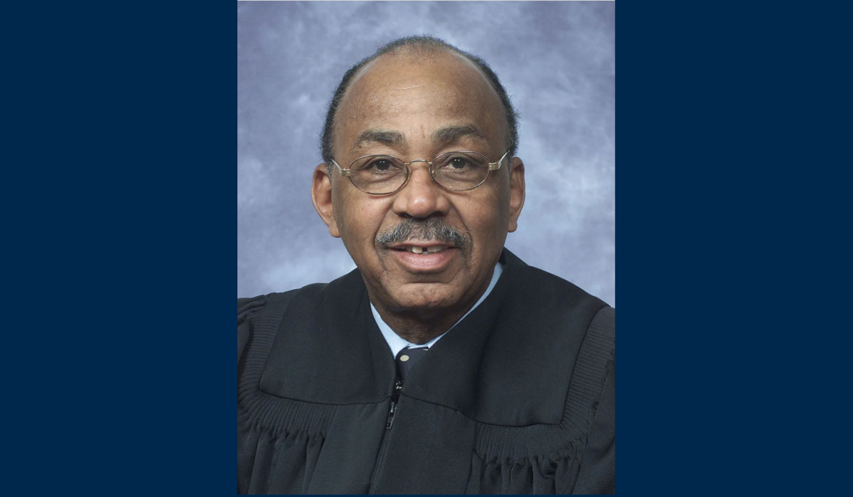A headshot of the Honorable Harold J. Hood in his judge robes on a blue background.