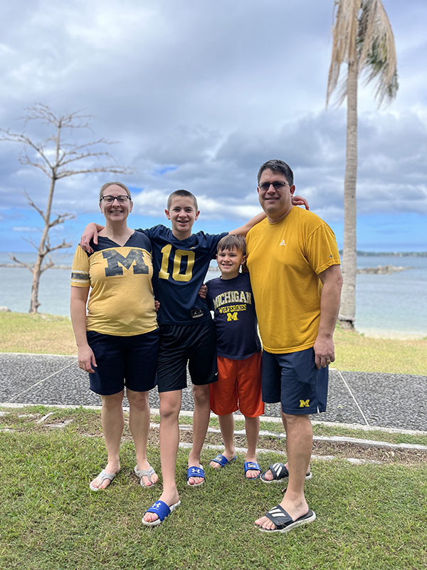 Jennifer Lessens Thompson ‘00, David Thompson ‘98, and their kids represent the Maize and Blue on a beach in the Philippines.