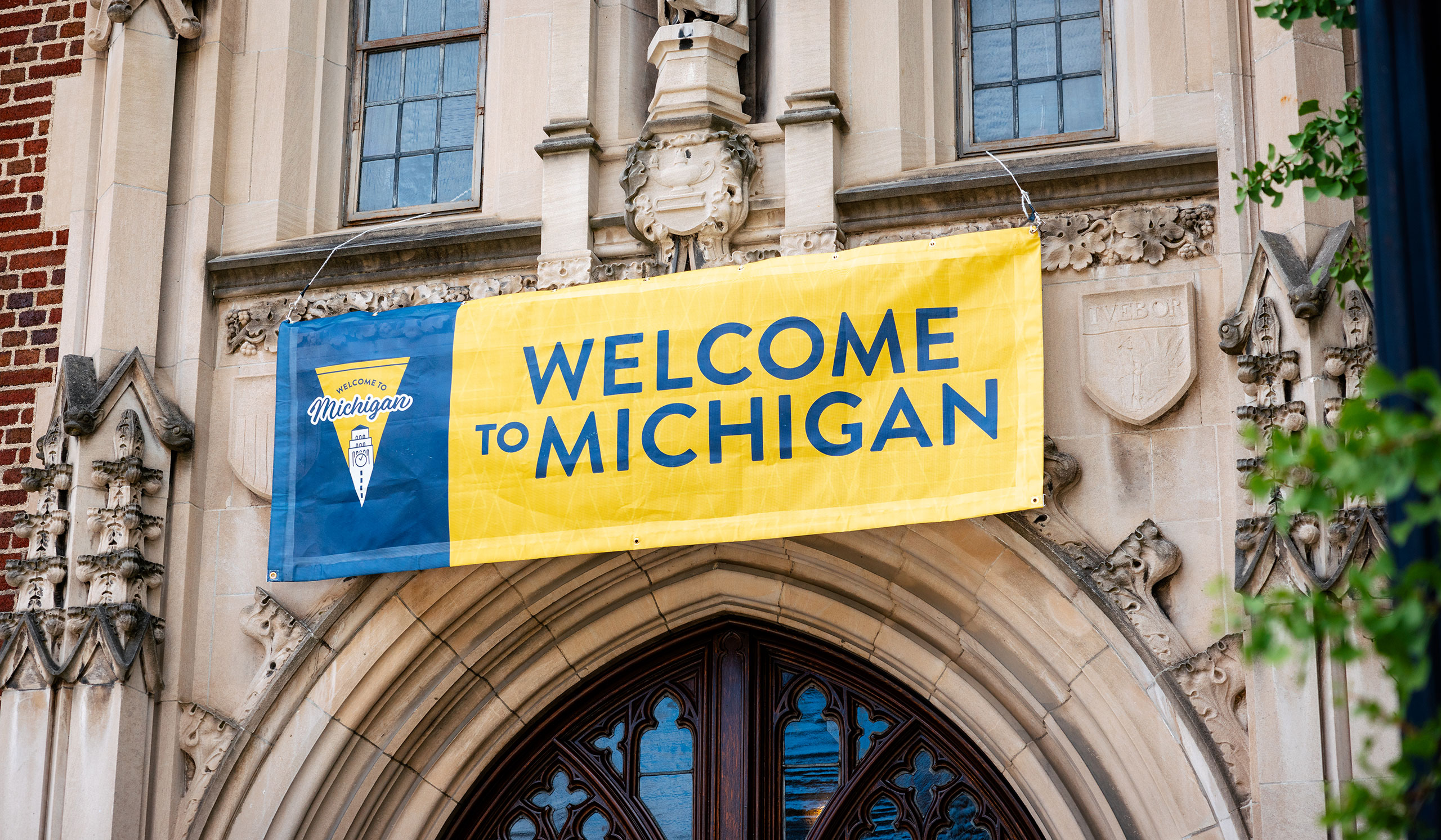 A "Welcome to Michigan" banner hangs above an entrance to a campus building.