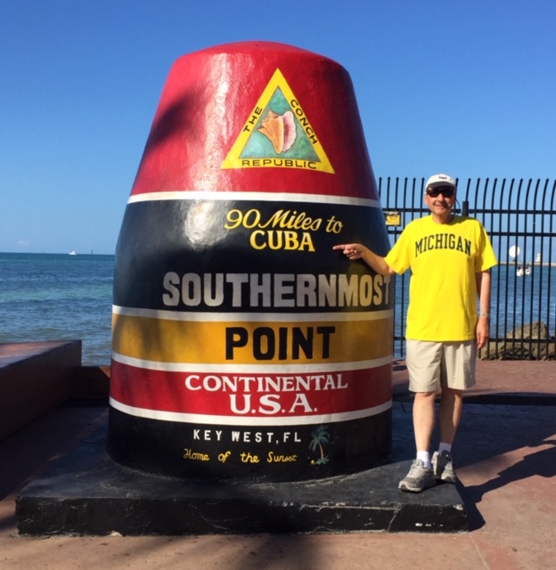 Jim Wolchok, ’77, points out the distance to Cuba on the Southernmost Point Buoy in Key West, Florida.