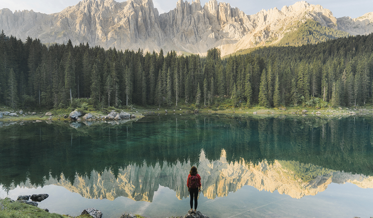 Woman Standing And Looking At Lago Di Carezza In Dolomites