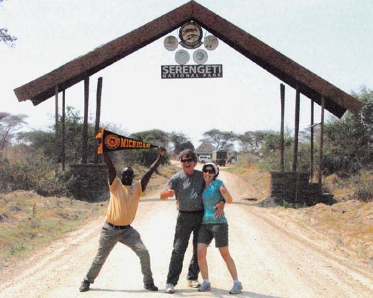Bob, ’76, and Gabbi Crum get their tour guide, Willy, into the Michigan spirit at the Serengeti National Park in Tanzania.