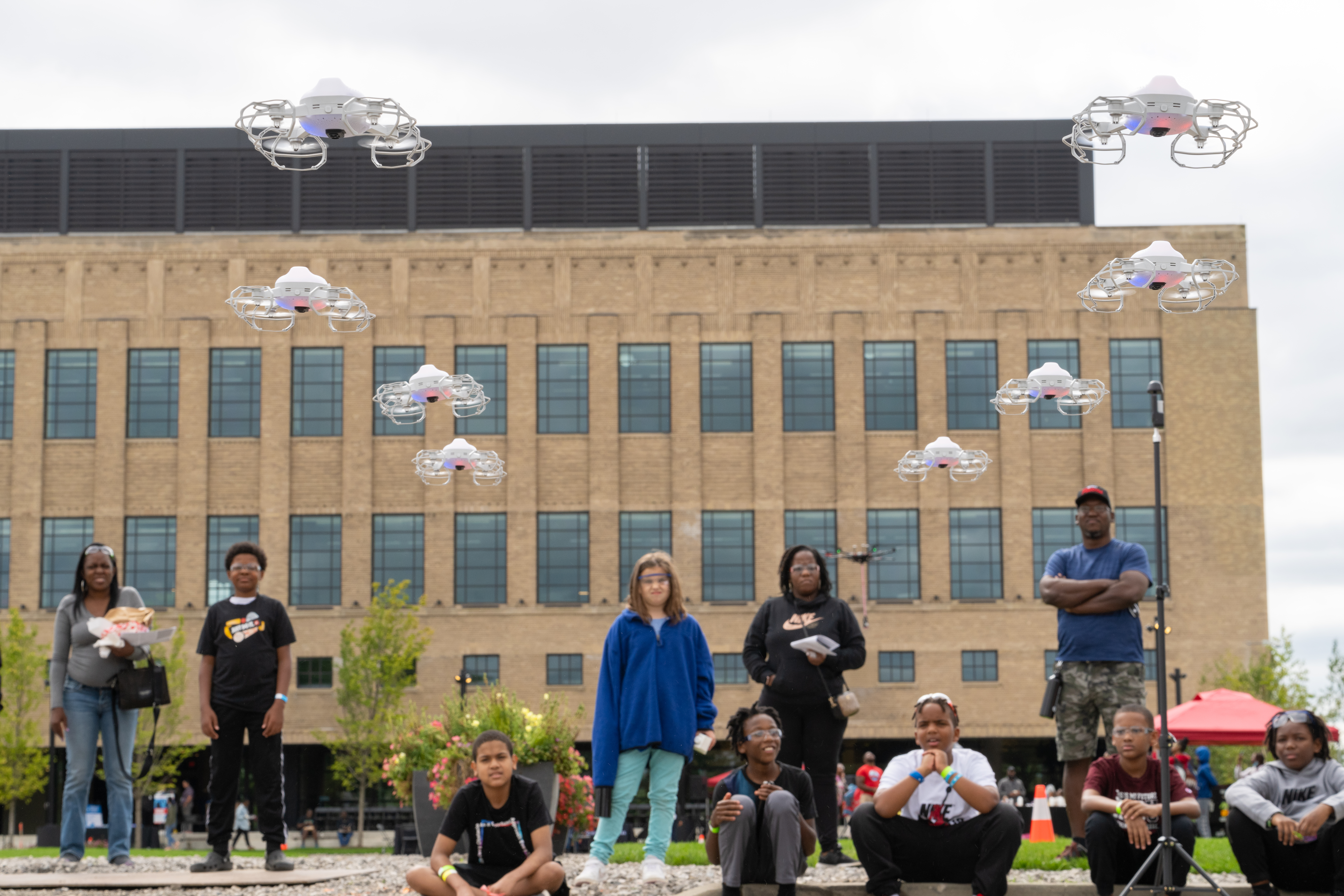 Young children fly drones near Michigan Central Station.