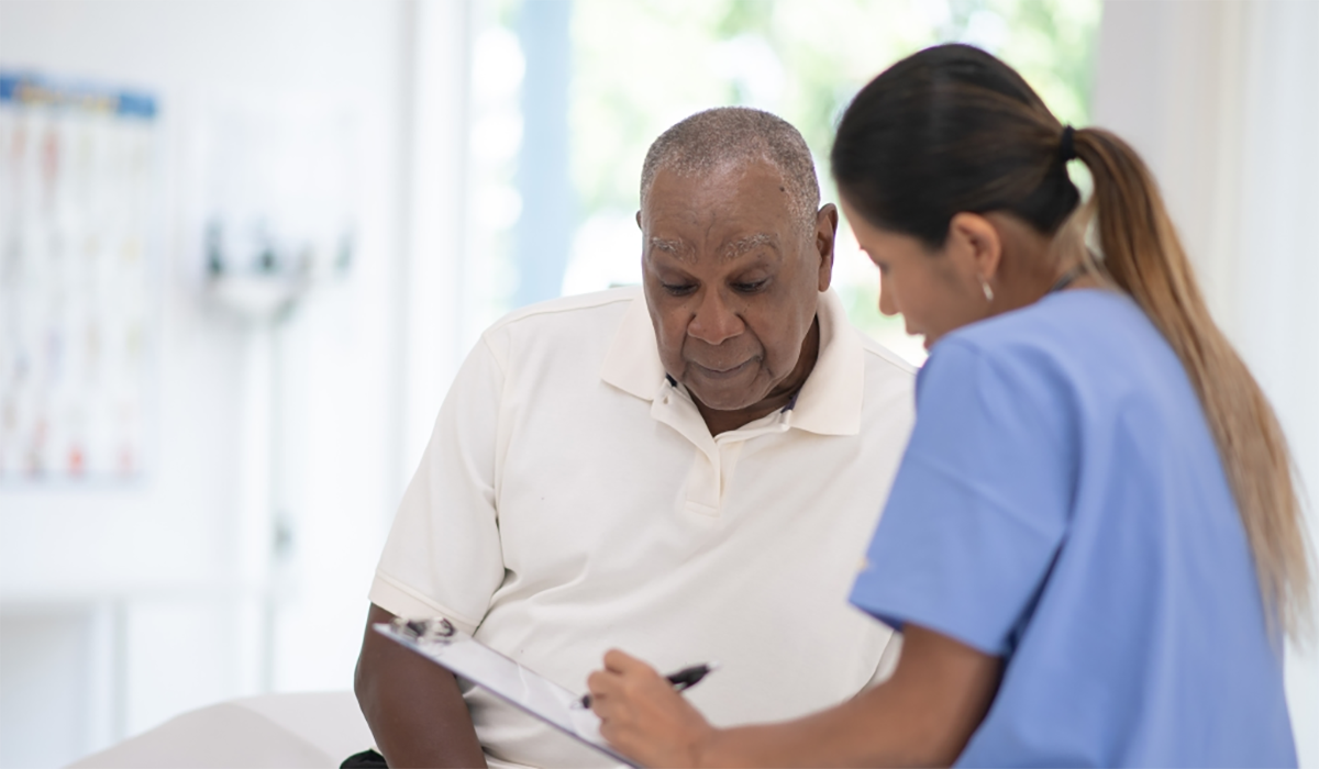 Older Black Man With Doctor In Exam Room