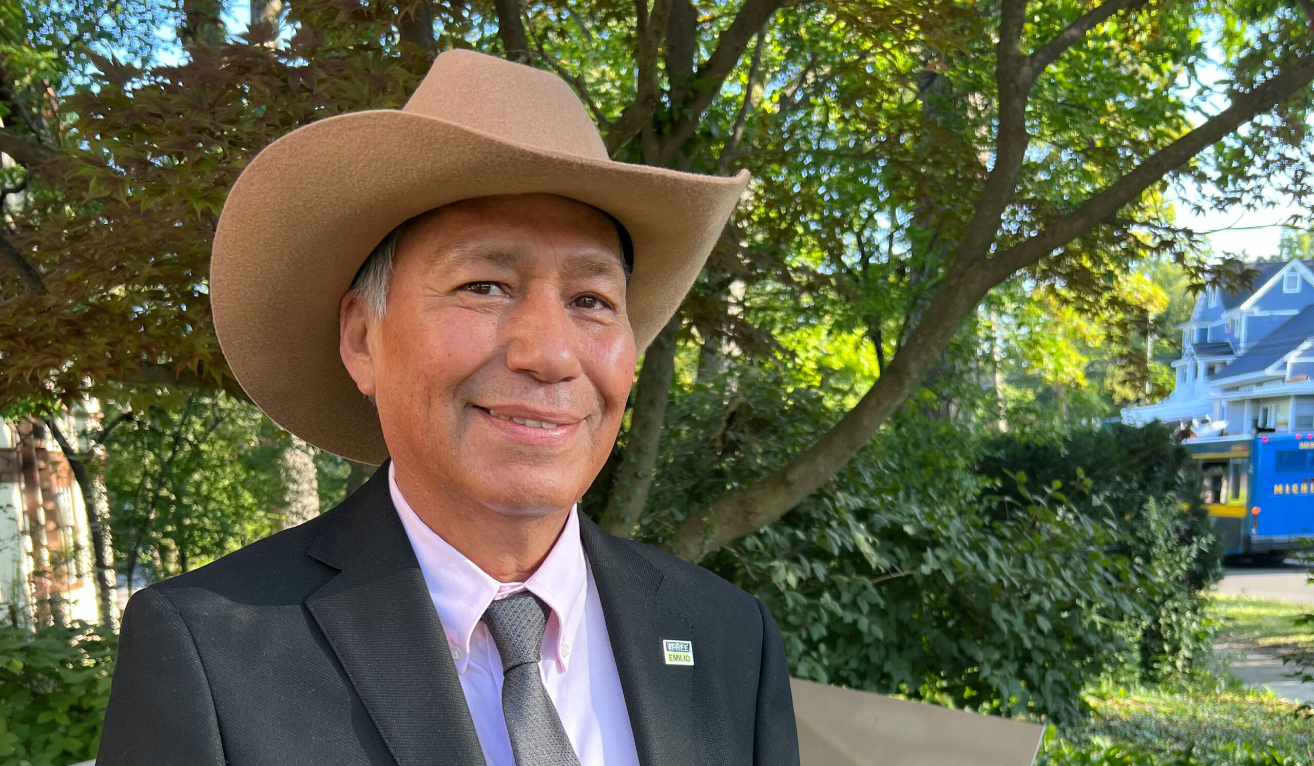 Emilio Gutiérrez Soto, wearing a suit and a cowboy hat, smiles with trees in the background.
