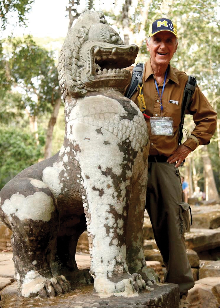A millennia-old guardian lion at the Ta Prohm temple in Cambodia continues its vigil as Peter Eckstein, ’58, poses with it.