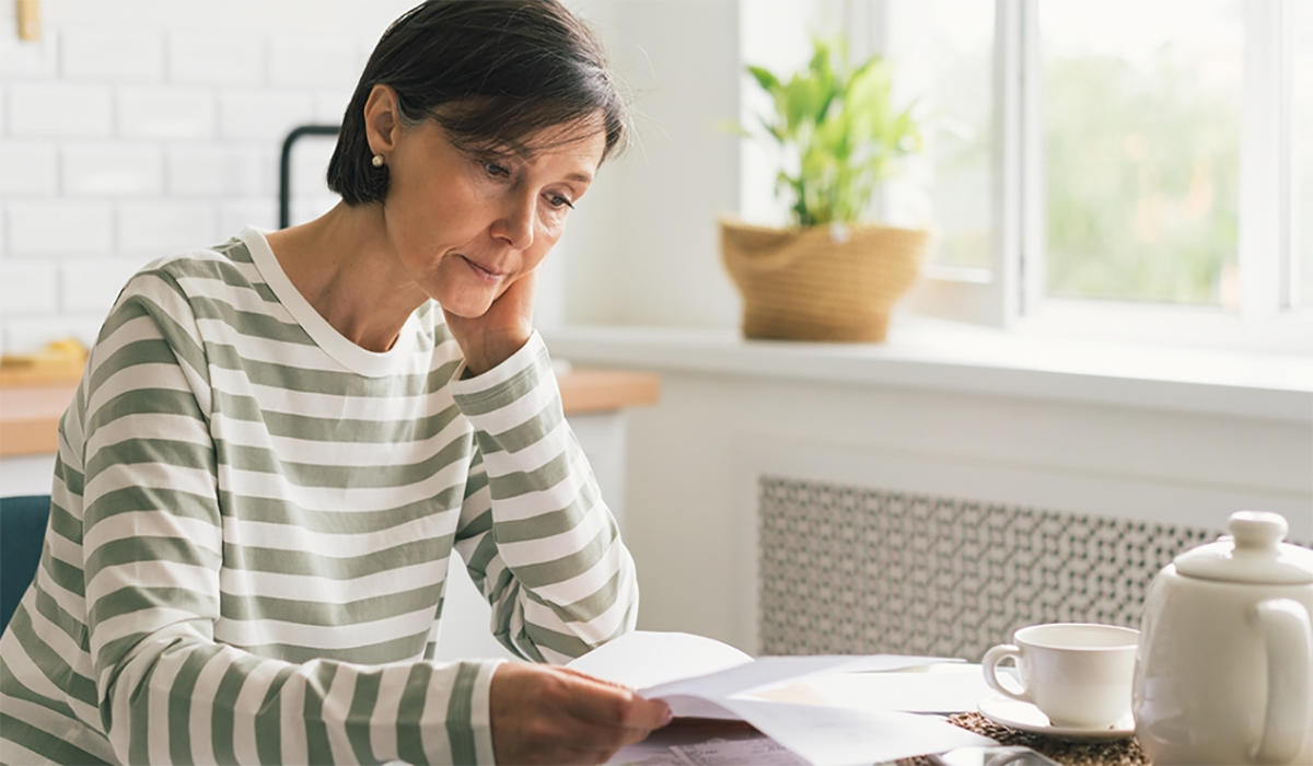 Woman Sitting At Table Looking At Papers Low